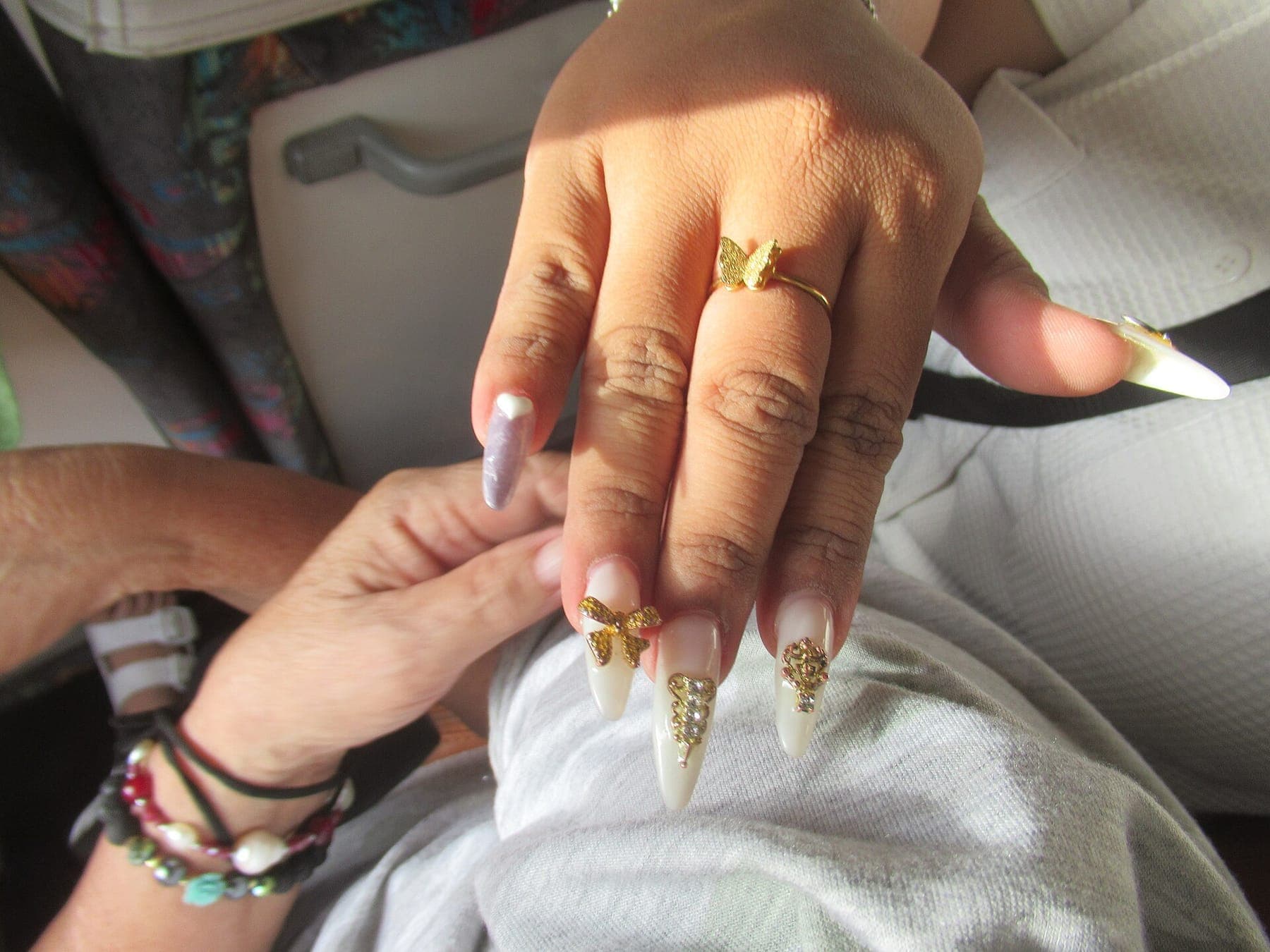 Long stiletto nails finished with gold charms and rhinestones
